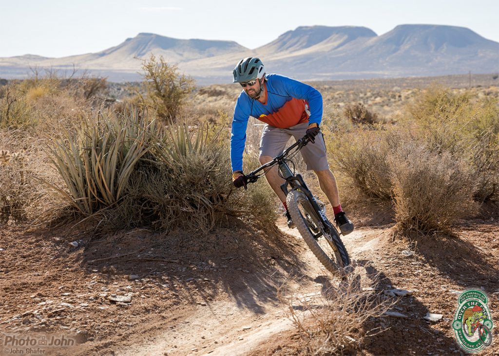 A mountain biker riding a bike through a corner in the desert. 