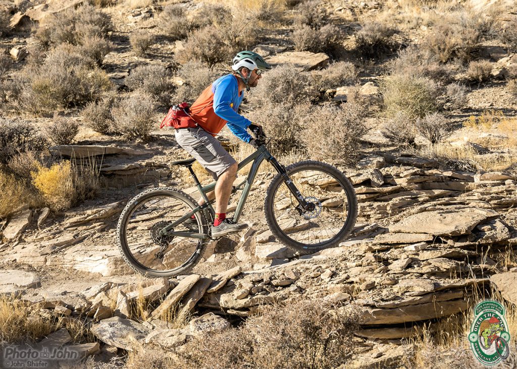 A mountain biker pedaling uphill on a rocky trail. 