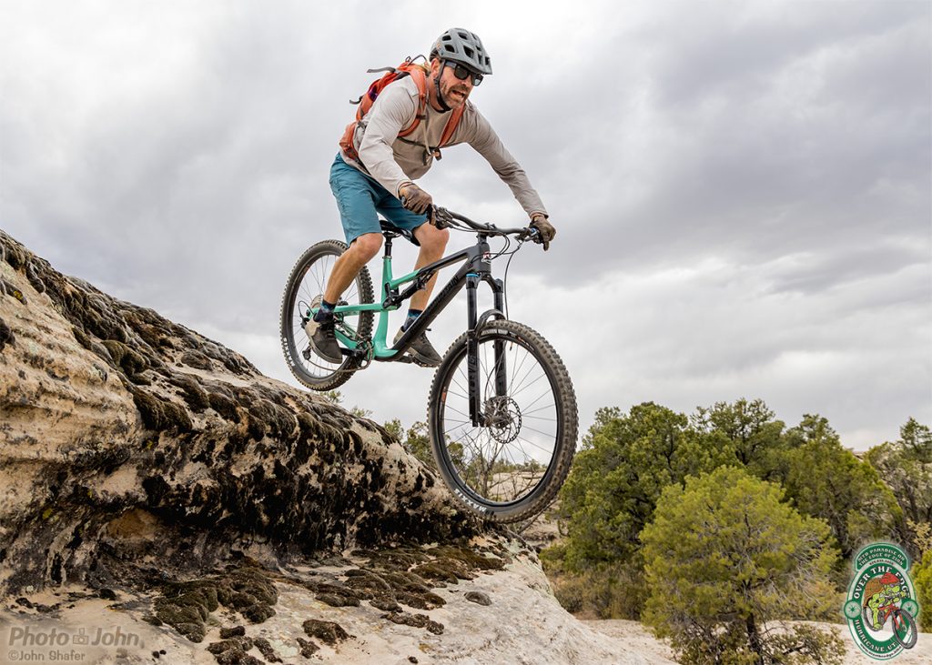 A mountain biker jumps of a mossy rock drop in the Southern Utah desert. 