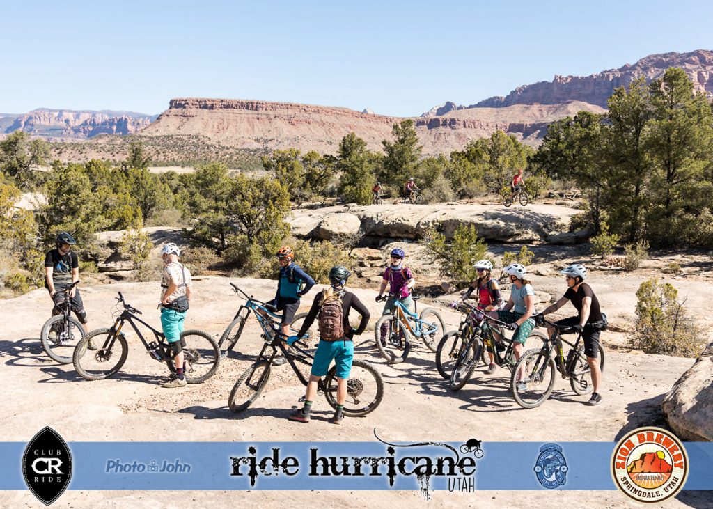 A group of mountain bikers hanging out on a rock in a dramatic Southern Utah desert landscape. 