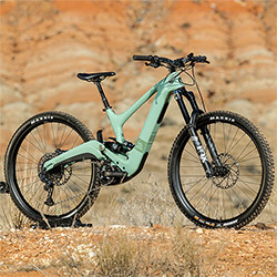 Thumbnail photo of a mint green Ibis Oso E-MTB mountain bike with a colorful, out-of-focus Southwestern background.