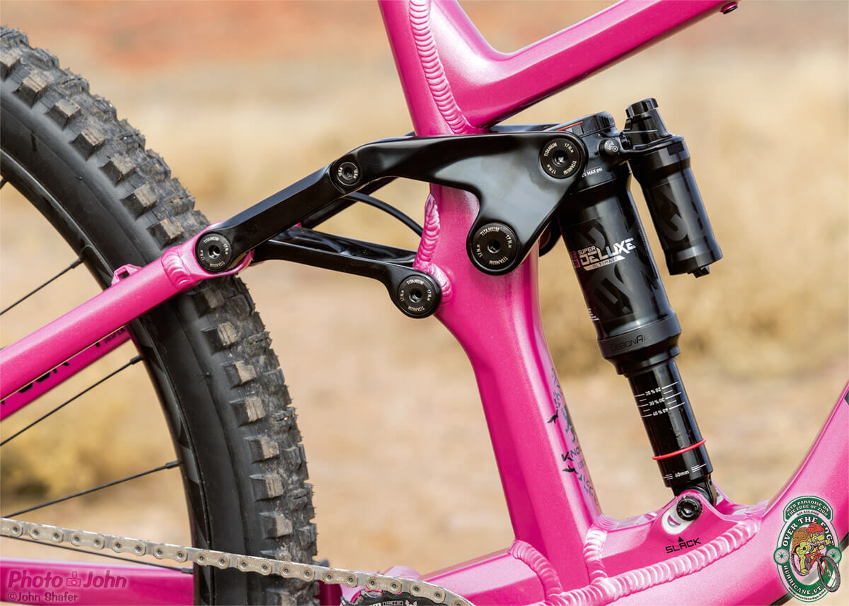 A photo of a black mountain bike rear linkage system on a bright pink bike.