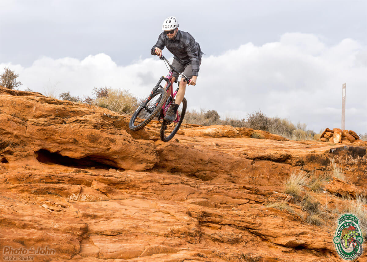 Photo of a mountain biker launching off a big wall of red, Southern Utah slickrock. 