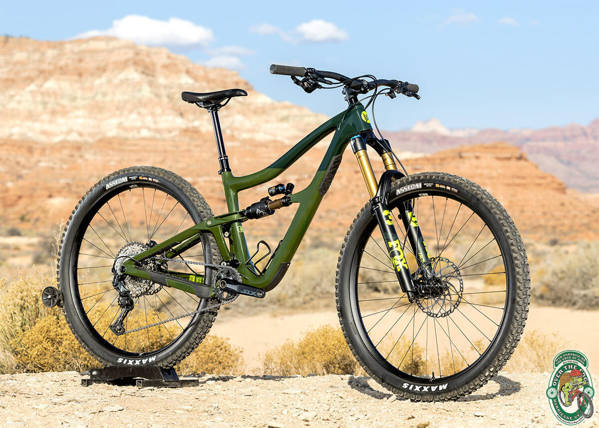 A dark-green, two-tone full-suspension mountain bike in a bright, Southern Utah landscape. 