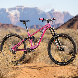 Thumbnail photo of a bright pink full-suspension Knolly mountain bike with the cliffs of Zion National Park in the background.